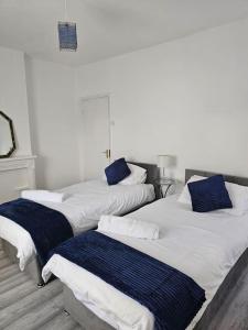 Tres camas en una habitación con almohadas azules. en Luxury Home in Lewisham, en Bromley