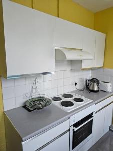 a kitchen with a stove top oven and white cabinets at Luxury Home in Lewisham in Bromley