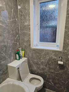 baño con aseo blanco y ventana en Luxury Home in Lewisham, en Bromley