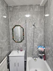 a bathroom with a sink and a mirror and a tub at Luxury Home in Lewisham in Bromley