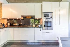 a white kitchen with white cabinets and appliances at Villa Jasmine in Aroeira