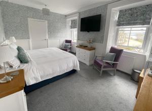 a bedroom with a bed and two chairs and a tv at Kilmory House in Lochgilphead
