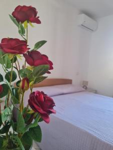 un vase avec des roses rouges à côté d'un lit dans l'établissement Casa Vacanza Pula, à Pula