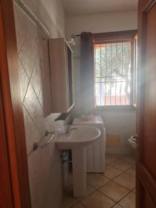 La salle de bains blanche est pourvue d'un lavabo et d'une fenêtre. dans l'établissement Casa Vacanza Pula, à Pula
