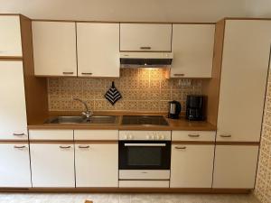 a kitchen with white cabinets and a sink at Ferienwohnung Rappl in Schleching