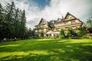 une grande maison avec une grande pelouse devant elle dans l'établissement Willa Cztery Pory Roku, à Kościelisko