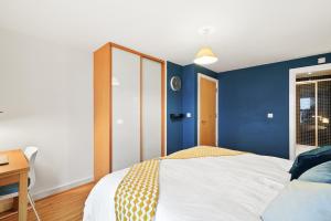 Schlafzimmer mit blauen Wänden, einem Bett und einem Schreibtisch in der Unterkunft Central Bishops Stortford 2BR Apartment in Bishops Stortford