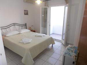 1 dormitorio con 1 cama y puerta a un balcón en Glaros Rooms en Koufonisia