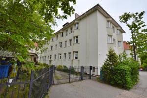 a white building with a fence in front of it at Victus Apartamenty, Apartament Madera in Sopot