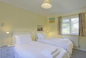 a bedroom with two beds with white sheets and a window at Sparrows, Wangford nr Southwold in Wangford