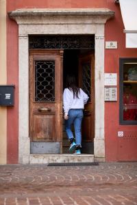 Una donna in piedi sulla porta di un palazzo di Casa Morellato a Riva del Garda