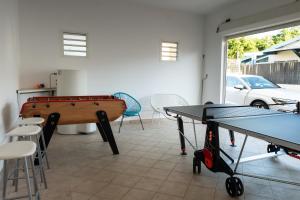 a room with a ping pong table and some chairs at Villa Paola - Piscine, billard - Au Nord de l'île in Sainte-Marie