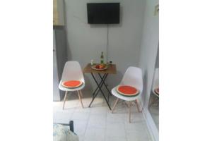 um quarto com duas cadeiras e uma mesa com televisão em Olga Studios em Heraclião