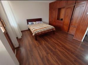 1 dormitorio con 1 cama y suelo de madera en Departamento Gigante de 4 dormitorios. Ecualodge 23, en Cuenca