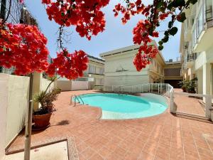 a swimming pool in a courtyard with red flowers at Apartamento Deluxe Ciudad Jardin in Las Palmas de Gran Canaria