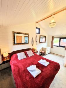 um quarto com uma grande cama vermelha com toalhas em Beaver 1 HuntersMoon-warminster-Wiltshire em Warminster