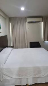 een slaapkamer met een wit bed en een raam bij Mont Blanc Apart Hotel Quarto 102 in Duque de Caxias
