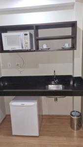 a kitchen counter with a sink and a microwave at Mont Blanc Apart Hotel Quarto 102 in Duque de Caxias