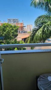 a balcony with a view of a palm tree and buildings at Mont Blanc Apart Hotel Quarto 102 in Duque de Caxias