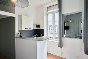 eine weiße Küche mit Spüle und Fenster in der Unterkunft Lille Saint Maurice - Nice and functional studio in Lille