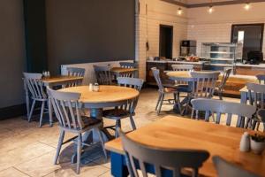 een restaurant met houten tafels en stoelen en een keuken bij The Pavilion Bisley in Bisley