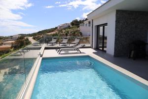 a swimming pool with chairs and a house at Villa-soleil-levant vue mer panoramique in Sari Solenzara