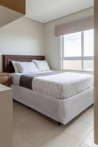 a white bedroom with a large bed with a window at PALMAS EXPERIENCE - APARTAMENTO BRISA, melhor localização in Palmas