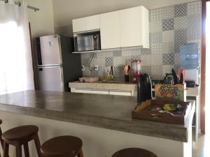 uma cozinha com um balcão com bancos e um frigorífico em Casa Morena Luz - espaço e conforto, perto da praia em Cumuruxatiba