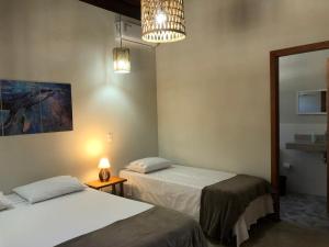 um quarto com duas camas, um candeeiro e um espelho em Casa Morena Luz - espaço e conforto, perto da praia em Cumuruxatiba