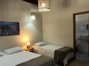 a room with two beds and a lamp and a mirror at Casa Morena Luz - espaço e conforto, perto da praia in Cumuruxatiba