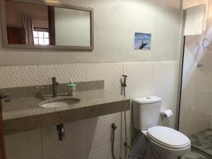 a bathroom with a toilet and a sink and a mirror at Casa Morena Luz - espaço e conforto, perto da praia in Cumuruxatiba