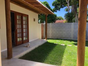 um cão deitado na relva em frente a uma casa em Casa Morena Luz - espaço e conforto, perto da praia em Cumuruxatiba