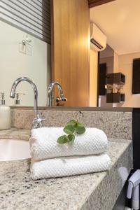 a bathroom counter with two towels and two faucets at PALMAS EXPERIENCE - APARTAMENTO BRISA, melhor localização in Palmas