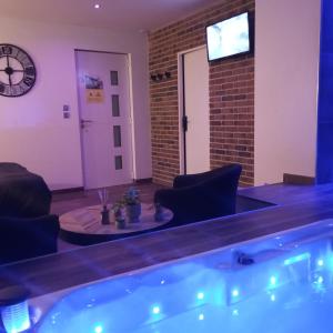 a hot tub in a room with a clock on the wall at chambre romantique avec spa privatif in Ferrière-la-Grande