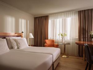 Habitación de hotel con cama, escritorio y ventana en Precise Tale Seehof Davos en Davos