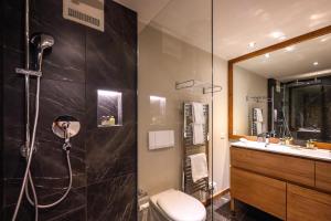 a bathroom with a shower and a toilet and a sink at Precise Tale Seehof Davos in Davos