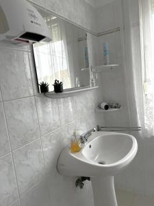 a white bathroom with a sink and a mirror at Apartment Révész in Harkány