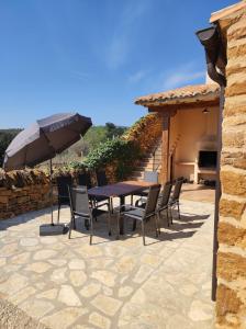 a patio with a table and chairs and an umbrella at masia riu dels arbres in Benasal