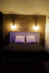 a bedroom with a bed with a brick wall at chambre romantique avec spa privatif in Ferrière-la-Grande