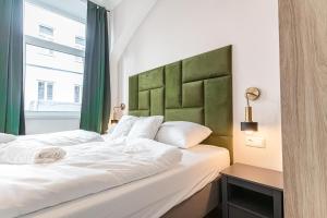 a bedroom with a large white bed with a green headboard at Westbahnhof Kingbed 1BR Apt with ensuite washer in Vienna