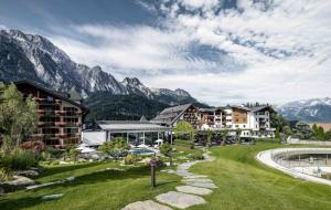 a resort with a pool and mountains in the background at Hotel Krallerhof in Leogang