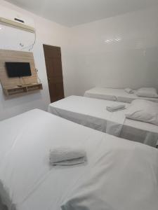 a room with three beds and a tv on the wall at Pousada Santo Amaro in Juazeiro do Norte