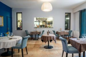 a restaurant with tables and chairs and a chandelier at La Redoniere in Romans-sur-Isère