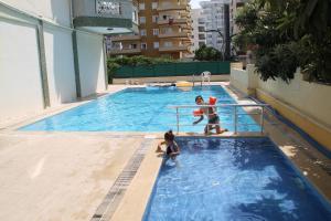 馬赫穆特拉爾的住宿－阿伊岡公寓，男人和孩子在游泳池玩耍