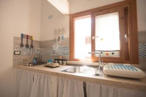eine Küchentheke mit einem Waschbecken und einem Fenster in der Unterkunft La Casetta nel Porto in Castellammare del Golfo