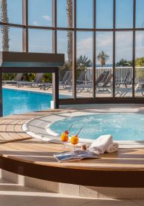 馬賽的住宿－金色鬱金香馬西利亞別墅酒店，游泳池前的桌子上摆放着两杯饮料的游泳池