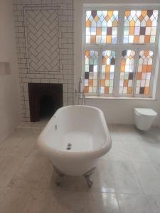 a bathroom with a white bath tub and stained glass windows at Remarkable 7-Bed House in London in London