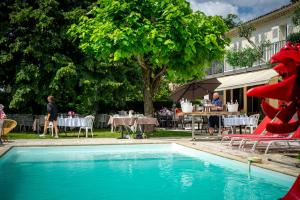 una piscina con un dragón rojo junto a un restaurante en La Redoniere, en Romans-sur-Isère