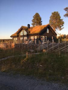 a house with a wooden fence in a field at New and cozy family cabin on Golsfjellet in Golsfjellet