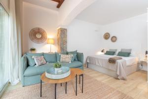 a living room with a blue couch and a bed at Bacom House completa in Caldes de Malavella